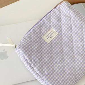 Macro detail of purple checkered quilted makeup bag with zipper on a white laptop