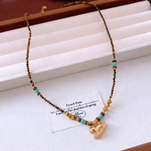 Détail du pendentif cheval à bascule plaqué or 18 carats sur collier en oeil de tigre