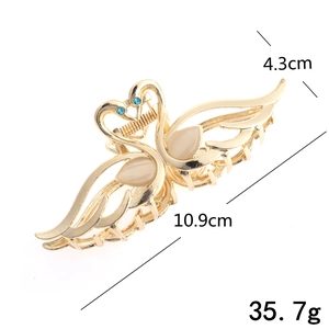 Golden swan hair claw clip with opal stone wings and blue diamond eye detail