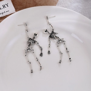 Detailed close-up of vintage silver skeleton earrings with movable joints on ceramic plate