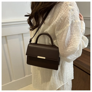 Détail d'un sac à main en cuir marron foncé avec fermoir doré et bandoulière réglable