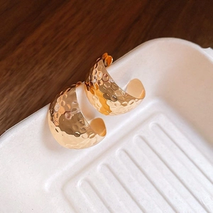 Detailed macro view of 14K gold plated earrings with a hammered metal texture finish