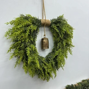 Macro detail of heart-shaped cedar wreath with bronze bell and rustic jute rope hanging