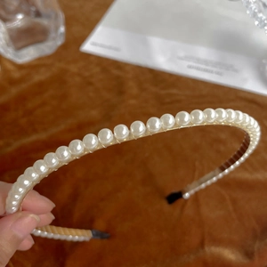 Detailed view of elegant white pearls on a metal headband with black protective tips