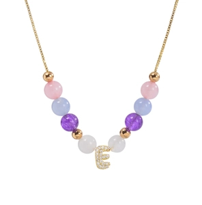 Gros plan du pendentif lettre E avec perles roses et bleues sur collier en or