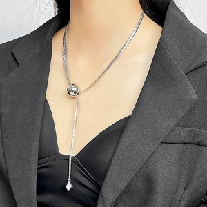 Detail of silver snake chain necklace with polished sphere pendants on female model