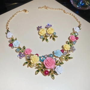 Macro shot of floral necklace with pink roses, pearls, and crystals on a gold chain