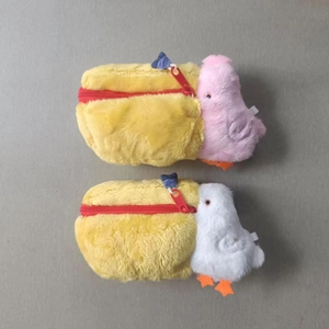 Detail of yellow plush pelican bags with red zippers and cute small bird charms