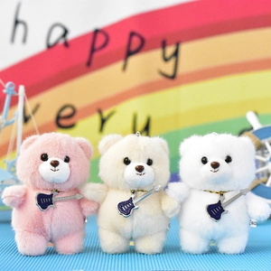 Close-up of three cute plush bears with guitar pendants in pink, cream, and white.
