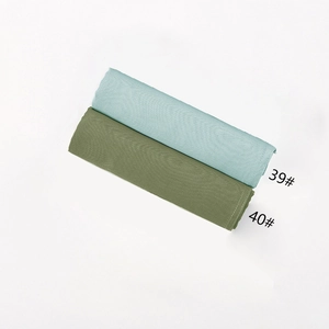 Detail showing folded light blue and olive green hijabs with micro-wrinkle texture