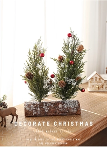 Close-up of dual mini snow-flocked Christmas trees on a wooden base with red berries
