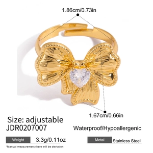 Dettaglio anello fiocco dorato con zircone a cuore e fascia regolabile in acciaio inox