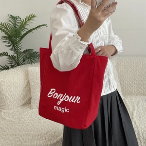 Detail of red canvas tote bag with Bonjour magic print and plaid strap lining