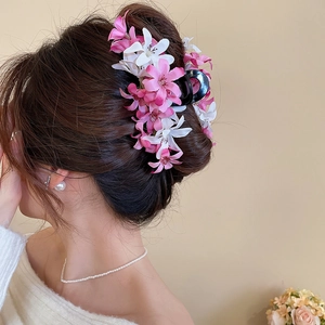 Détail de la pince à cheveux avec fleurs en tissu rose et blanc sur une coiffure relevée