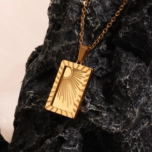 Macro shot of 18K gold plated rectangular sunburst pendant on a black stone background