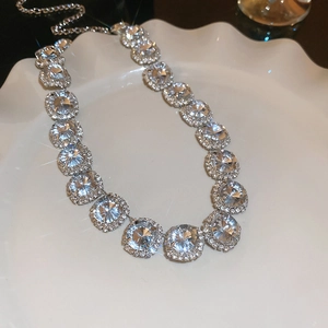Close-up of sparkling round zircon floral necklace on a white scalloped display tray