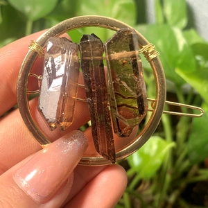 Close-up of natural smoky crystal stones hand-wrapped with gold wire on a round hair clip