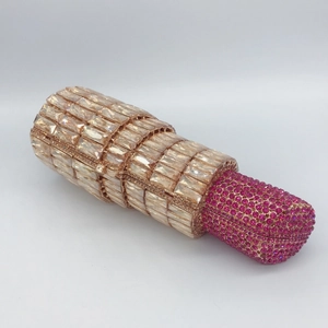Macro detail of luxury lipstick-shaped evening clutch with champagne and magenta crystals