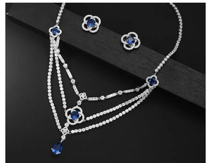 Macro shot of silver-colored layered necklace with blue stones on dark wood background