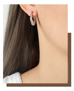 Detailed close-up of a silver and beige hoop earring worn by a model in a high-quality view