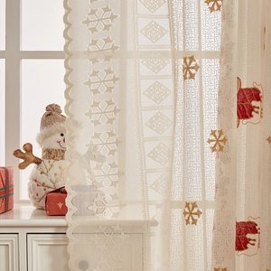 Close-up of Christmas lace curtain with reindeer and golden snowflake embroidery