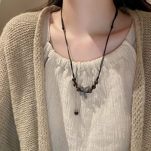 Detailed view of bohemian beaded necklace with butterfly pendant on woven cord