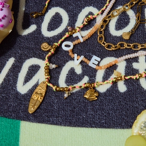 Macro detail of LOVE letter beads and summer charms on colorful woven cord jewelry