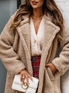 Detail of camel faux fur teddy coat texture with quilted crossbody bag and metal buckle