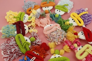 Flat lay of colorful handmade crochet monster key covers with metal rings on pink base