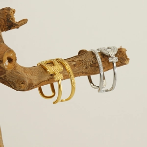 Detail of gold and silver open rings hanging on a branch with openwork and beaded texture