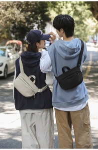 Rear view of couple wearing minimalist nylon cross-body bags in black and beige colors