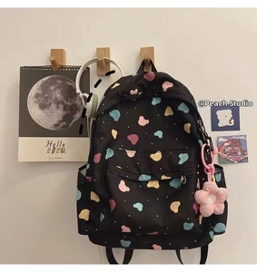 Detail of black canvas backpack with colorful bear prints and pink flower charm accessory