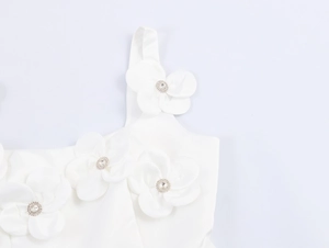 Dettaglio di un abito in raso bianco con fiori 3D con strass e spalline sottili
