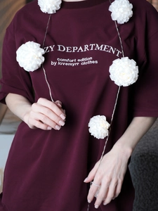 Close-up of wine red knitted t-shirt featuring white letter print and round neck detail