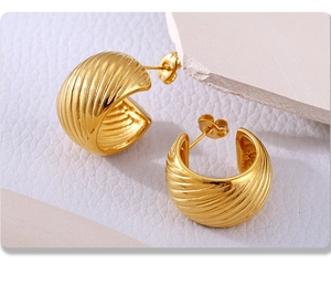 Macro view of C-shaped gold-plated stainless steel earrings with textured spiral pattern