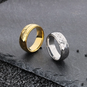 Close-up of gold and silver hammered texture titanium steel rings on dark rock