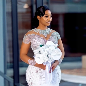 Elegant white lace wedding dress with silver beadwork and long train, shown on model outdoors