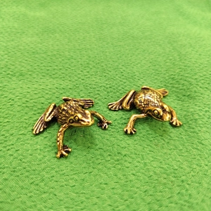 Detailed view of two vintage brass frog figurines with textured metallic finish