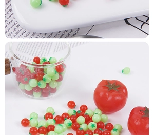 Dettaglio di mini pomodori da 0,6 cm in resina rossa e verde per casa delle bambole