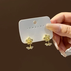 Detailed view of luxury gold flower earrings with full pavé crystals and central pearl