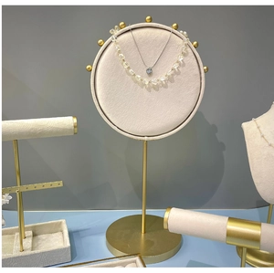 Détail du présentoir à bijoux en velours beige avec base en métal doré et supports