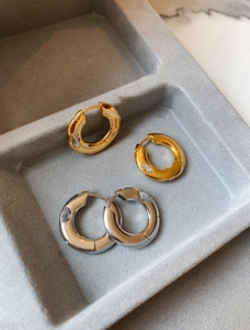 Detailed close-up of gold and silver hoop earrings with cubic zirconia in a jewelry box
