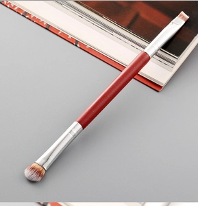 Dual-ended makeup brush detail with red glitter handle and silver metal ferrule tips