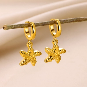Détail de boucles d'oreilles pendantes étoile de mer dorée sur une branche naturelle