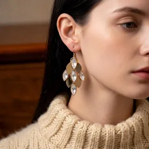 Vintage gold-plated drop earrings with leaf design and clear crystals on a female model