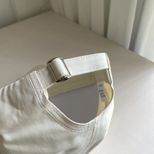 Detail of adjustable metal buckle and cotton fabric on the back of a white baseball cap