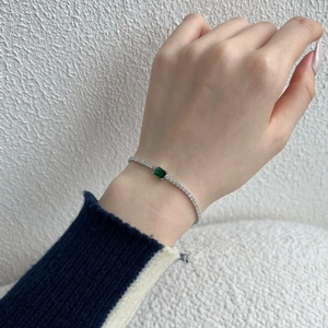Close-up of S925 silver clover bracelet with green zircon center stone on female wrist