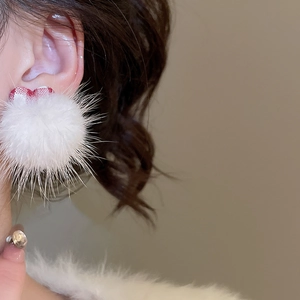 Close-up of white plush pom-pom earring with red plaid bow tie on model's ear