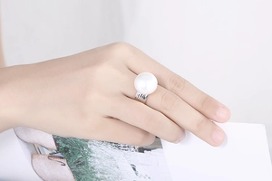 Close-up of a silver hammered ring with a large white pearl on a model's finger