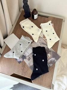 Detail of knitted polka dot socks in cream and gray on a decorative wooden tray